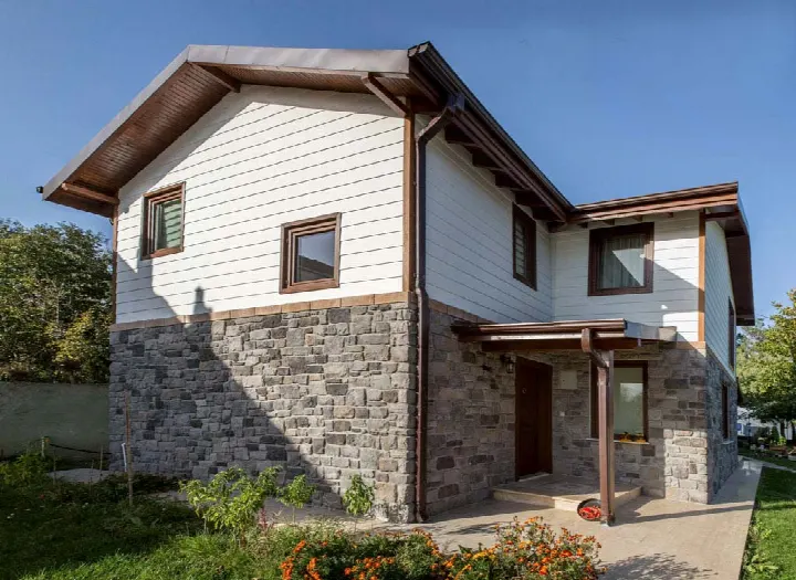 Villa zemin katında gri tonlu taş duvar kaplama, beyaz ahşap üst katla